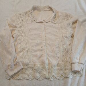 White lace trimmed blouse with a scalloped hem and embroidered details.